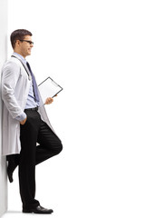 Doctor with a clipboard leaning against a wall