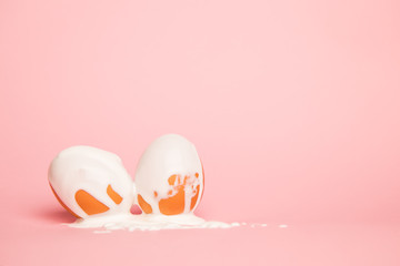 two Coloring Easter Eggs, Vibrant white  Paint pouring over an egg isolated on a Pastel pink Background. minimalism. the concept of Easter