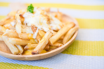 French Fries with Melted Cheese on wood bowl. Closeup of french fries with cheese.selective focus