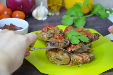 Young woman eating lamb on ribs with sauce and vegetables on green plate