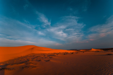 Fototapeta na wymiar Lonely sand dunes under amazing evening sunset sky at drought desert landscape. Global warming concept