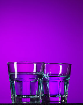 The water in two glassese on lilac background
