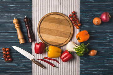 top view of ripe organic vegetables and cutting board on wooden table