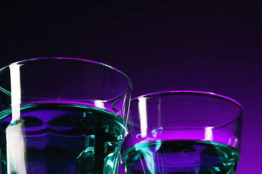 The water in two glassese on lilac background