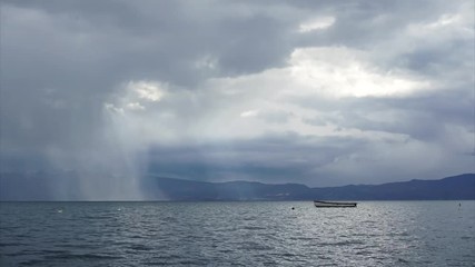 Timelapse of boat floating in Ohrid Lake against rainy clouds, Macedonia