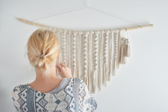 Macrame. Women's hobby. The girl makes a canvas of threads