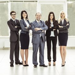 portrait of successful businessman and business team standing together with arms crossed in front of him
