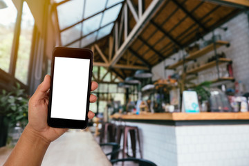 A man hand holding smart phone device in the coffee shop or cafe background.