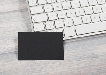 Business card in black color on computer keyboard. Mockup.