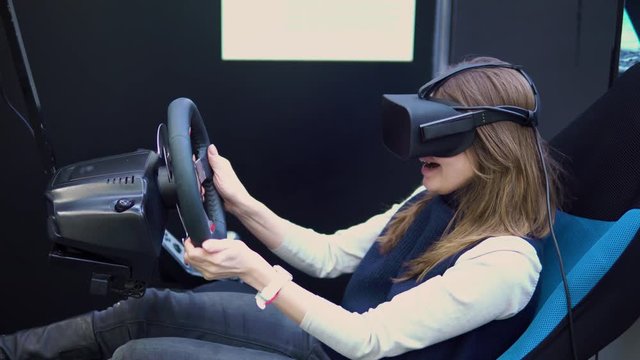 girl with virtual reality glasses controls the car racing simulator. Future technology concept. Testing the application in virtual reality