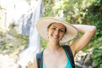 Attractive woman standing by waterfalls on his back