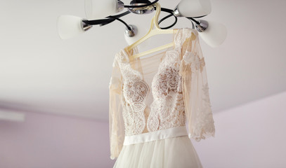 beautiful wedding dress hanging in the room, woman getting ready before  ceremony