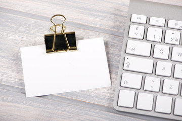 Business card in white color with gold clip next to computer key. Mockup.