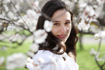 Fototapeta premium Portrait of a young woman against a background of blossoming apricot