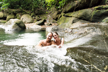Attractive couple under jungle waterfall