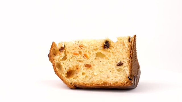 Part of panettone with raisins and dried apricots rotating in turn table isolated on white background.