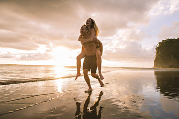 Couple in love having romantic tender moments at sunset on the beach - obrazy, fototapety, plakaty