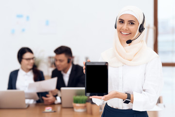 The woman in the hijab stands in the call center.