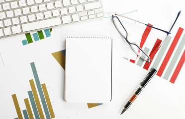 Notebook with several sheets with economics graphics and the keyboard of a computer. Mockup Copy space.