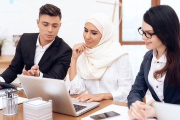 The Arab woman in hijab works in the office together with her colleagues.