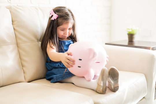 Upset little girl with empty piggy bank