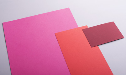 Cardboards of various colors next to business card of red color on gray background. Mockup.