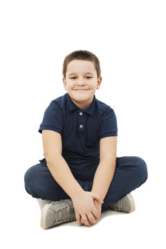 Portrait of a cute little boy sitting on the floor. Isolated on white background 