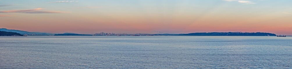 Pink twilight covered ocean at the sunset time. Sun is set already behind the mountains in on the horizon.