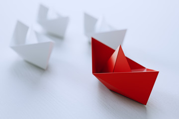 Leadership concept with red paper ship leading among white on white background.