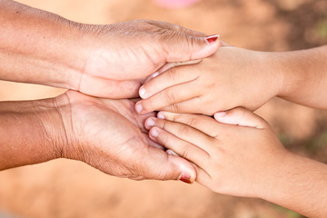 Hands of an elderly woman holding the hand of a younger woman