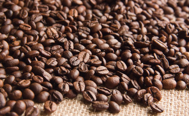 fried coffee beans are scattered on beige burlap cloth
