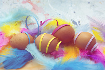 Fototapeta na wymiar Natural eggs with colorful feathers and confetti - Easter theme