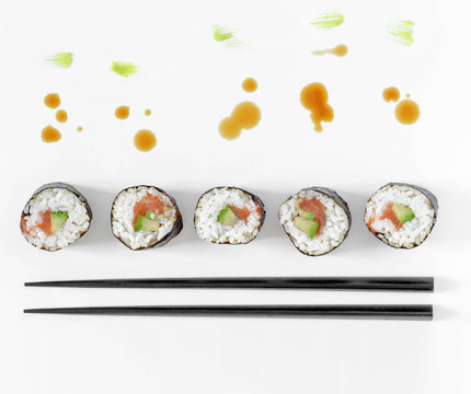 Sushi rolls and chopsticks with splashes of soy sauce and brush strokes of wasabi. Concept design.  Japanese cuisine.