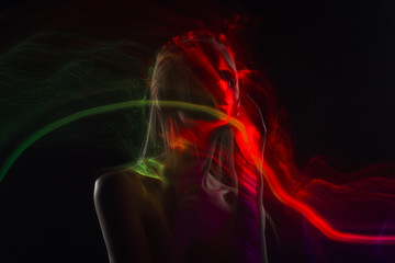 Conceptual avant-garde silhouette portrait of a beautiful blonde girl covered with multicolored lines applied by a lightbrush