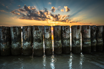 Sunset on beach with a wooden breakwater in Leba, Baltic Sea, Poland