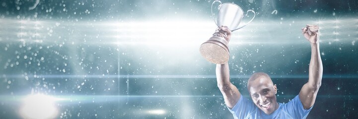 Portrait of happy sportsman cheering while holding trophy