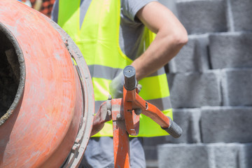 Construction worker on a cement / concrete mixer doing hard job.