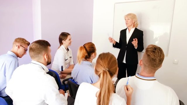 Female speaker giving presentation for students in lecture hall 
