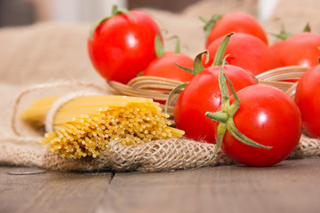 Long vermicelli pasta with cherry tomatoes matured on a wooden table on beige cloth