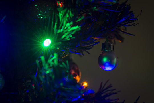 A shiny little Christmas ornament on a Christmas tree.