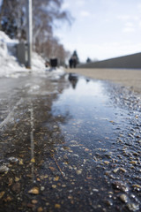 Water flows from the melting snow flowing along the asphalt. Spring melting snow.