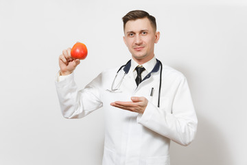 Smiling handsome young doctor man isolated on white background. Male doctor in medical uniform stethoscope holding red apple. Healthcare personnel health medicine concept. Proper nutrition. Copy space