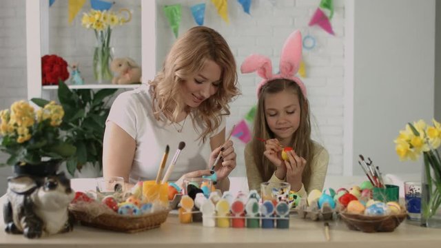 Mom and daughter paint eggs for Easter