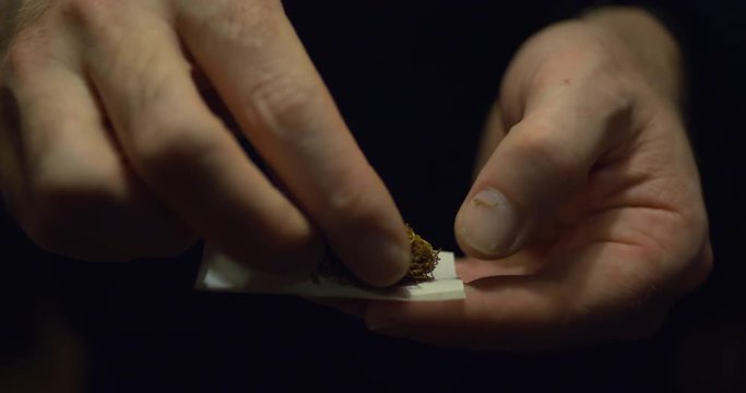 Man rolls tobacco cigarette in smoking paper