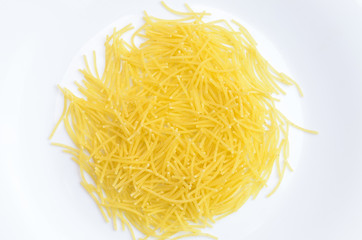Thin yellow pasta on a white plate.