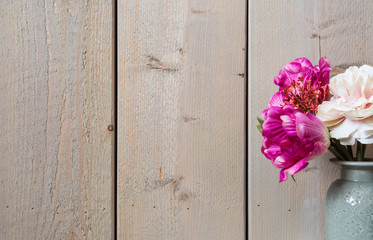 Pink flowers in ceramic vase spring decoration with wood wall background texture 