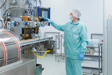 Naklejka premium Pharmacy industry factory man worker in protective clothing in sterile working conditions