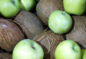 Close-up of a bunch of green apples and coconuts as background