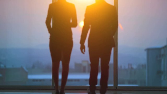 The man and a woman talking near the window on the sunny background