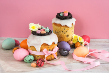Obraz premium Easter traditional cake with chocolate nest, candy and quail eggs decoration blossom flowers, colorful spring stillife in soft light and trendy pastel colors. Pink background